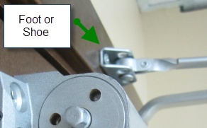A door closer that also shows the foot or shoe hardware above the closer.