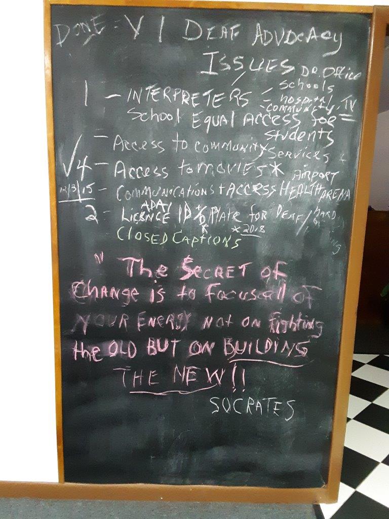 An image of ‘VI Deaf Advocacy Issues’ written on a chalkboard where advocates have written goals and objectives to work on. It lists community-focused goals like “1- Interpreters; 2-Access to community services; etc.”
