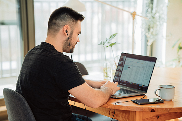 A man wearing earbuds in a Zoom meeting from his home office.